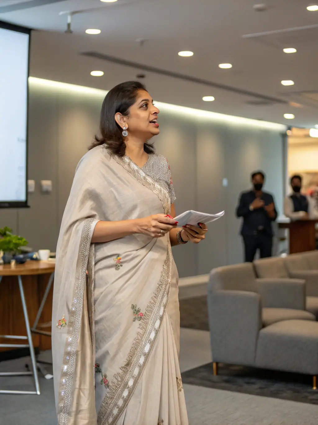 A professional Indian business woman giving a presentation to her team in a modern office setting, focusing on data analysis and strategic planning.